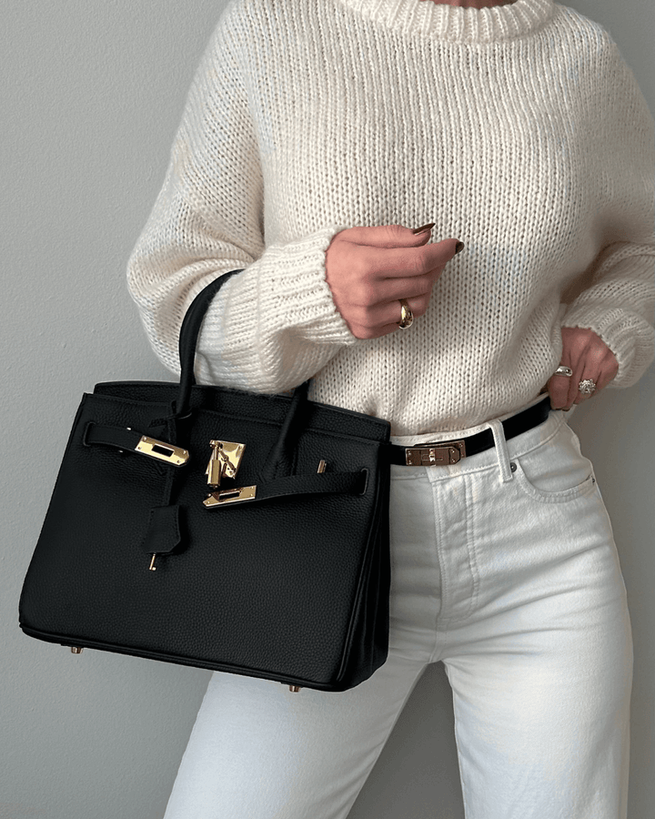 Woman wearing white sweater carrying black Madelyn handbag outdoors