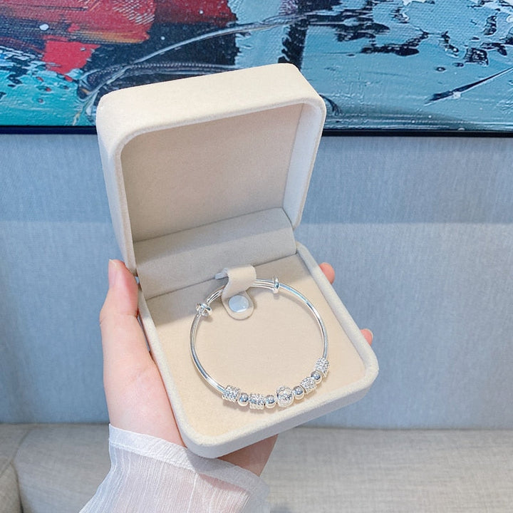 Stackable silver lucky beads bracelet paired with delicate wristwear
