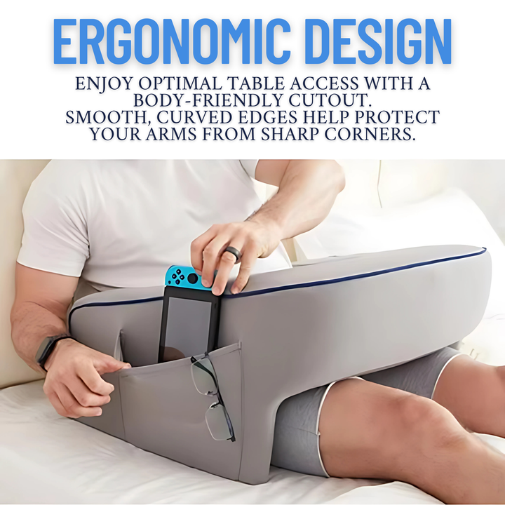 Man using a grey lap pillow on a bed with a gaming controller in the side pocket