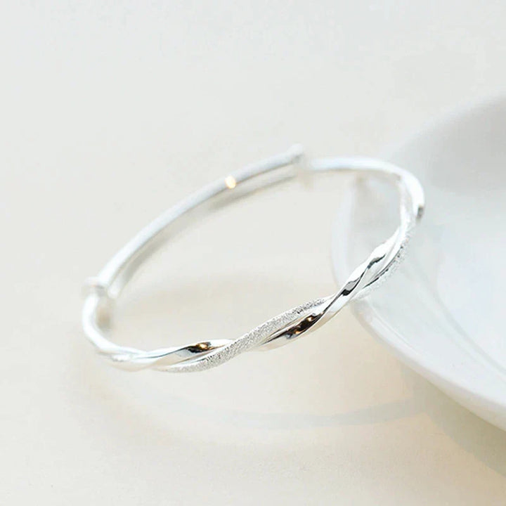 Silver bangle bracelet resting elegantly on a white surface