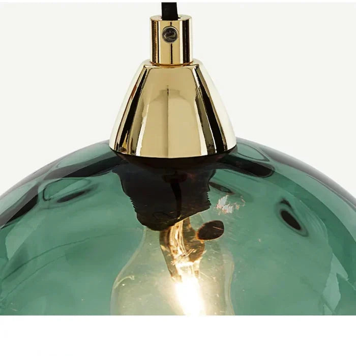 Close-up detail of a green glass globe shade and metallic gold hardware fitting
