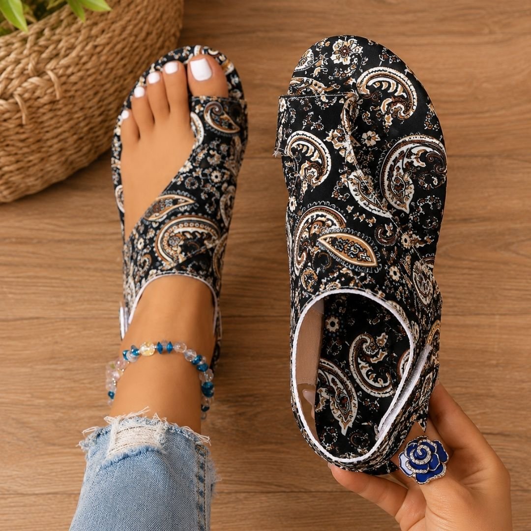 Woman holding black patterned orthopaedic sandal with intricate detailing