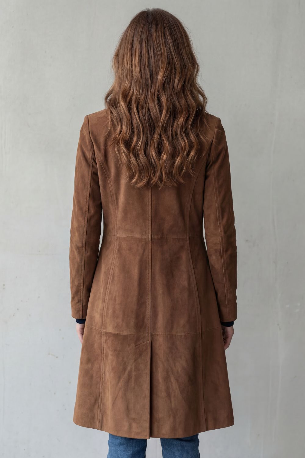 Back view of the brown long coat highlighting the tailored silhouette and vent