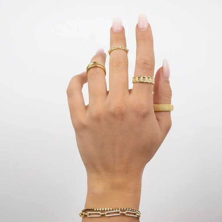 Hand wearing gold Aluna double band ring and matching stackable rings