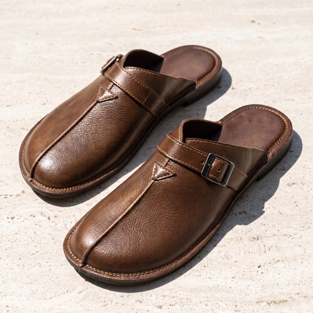 Brown Hudson buckle mules viewed from above on a textured surface