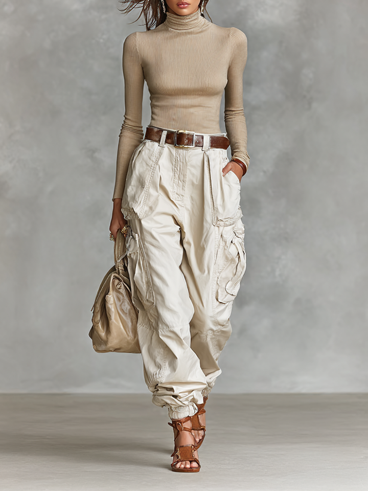 Model wearing a khaki high neck long sleeve top and utility cargo pants set with a brown belt and handbag.