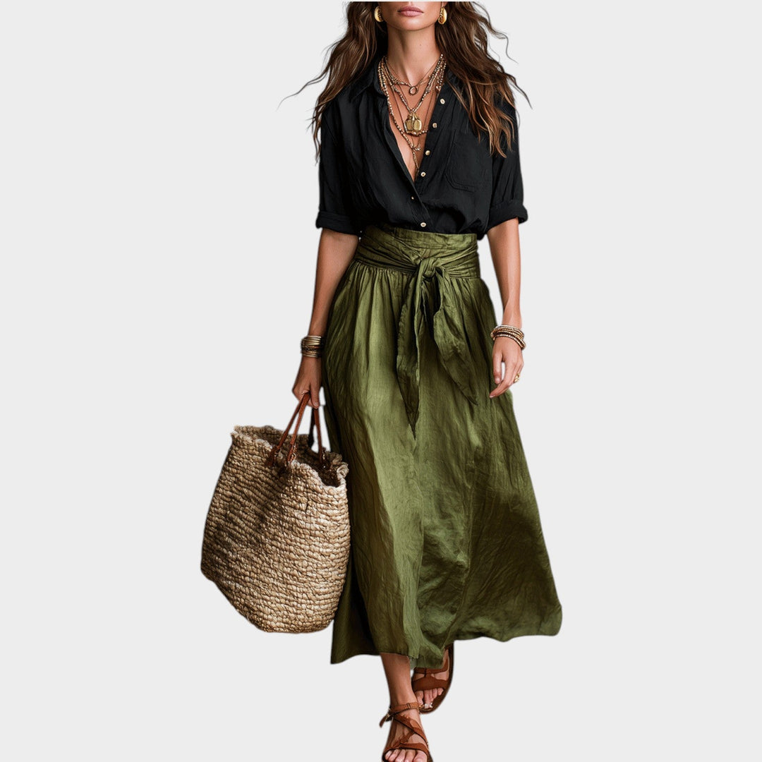 Woman wearing a black button-up shirt and green maxi skirt with a woven bag
