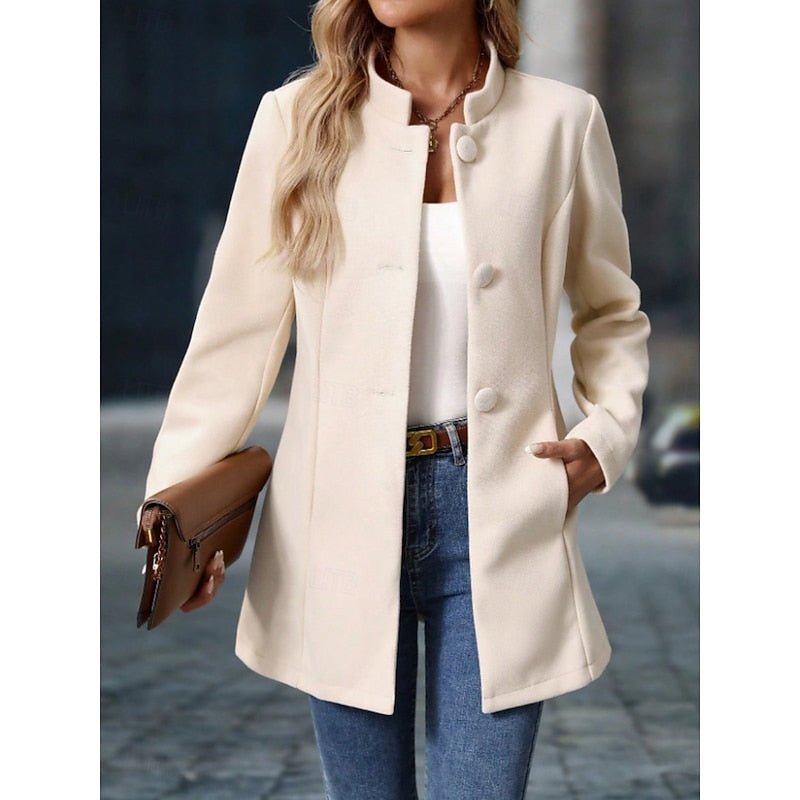 Woman wearing elegant apricot stand-collar trench coat outdoors holding a brown clutch