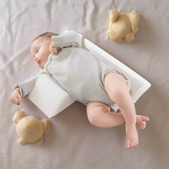 Overhead view of an infant sleeping comfortably with the triangular positioning pillow