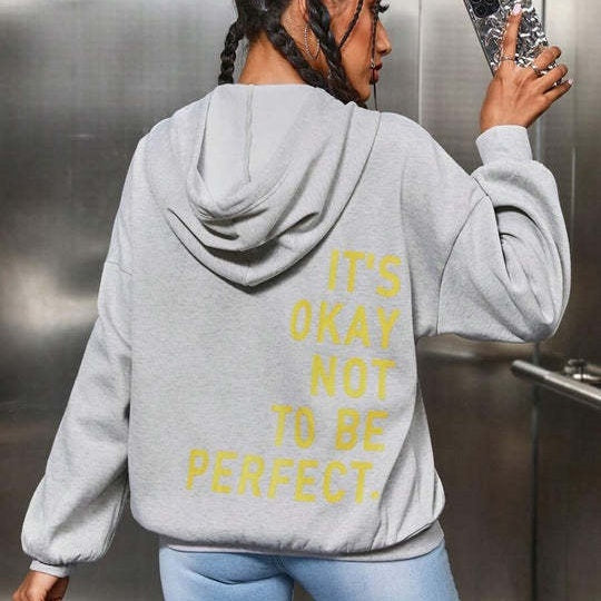 Back view of a woman wearing a grey relaxed hoodie with yellow letter print