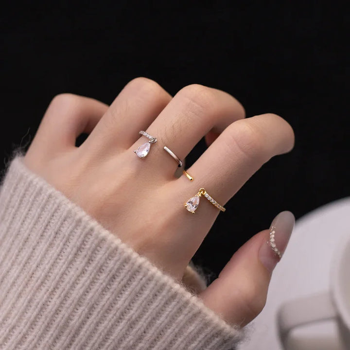 Hand wearing gold and silver adjustable teardrop rings