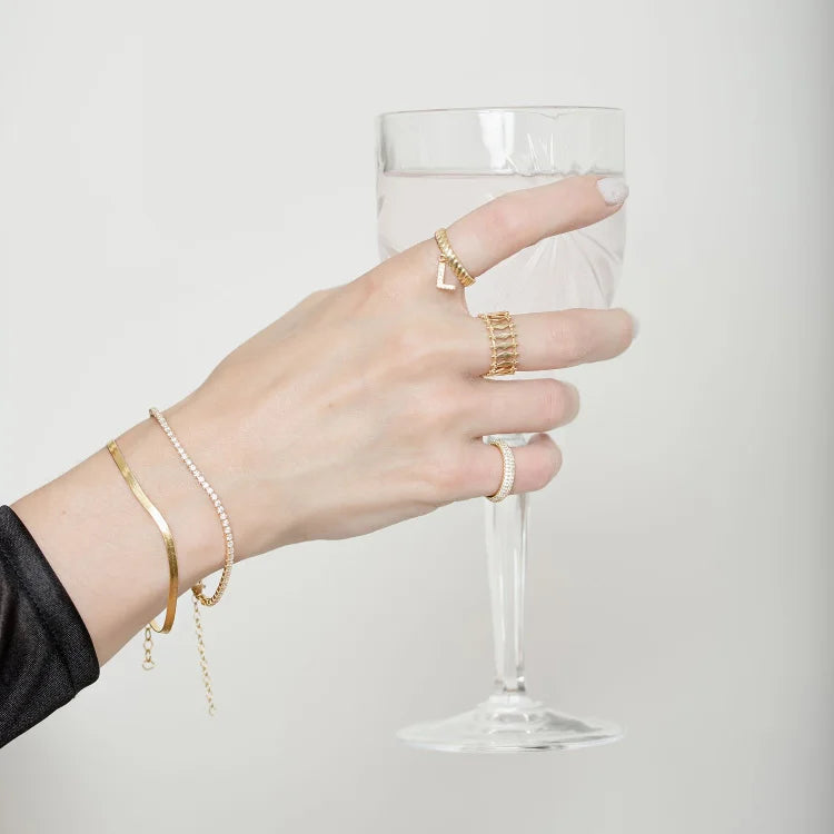 Woman wearing gold iced tennis bracelet holding a wine glass