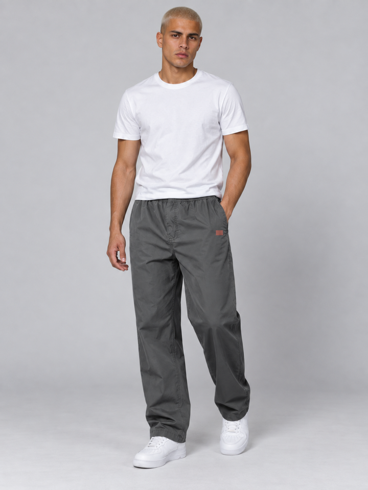 Flat lay of men's hiking trousers folded neatly with outdoor apparel accessories