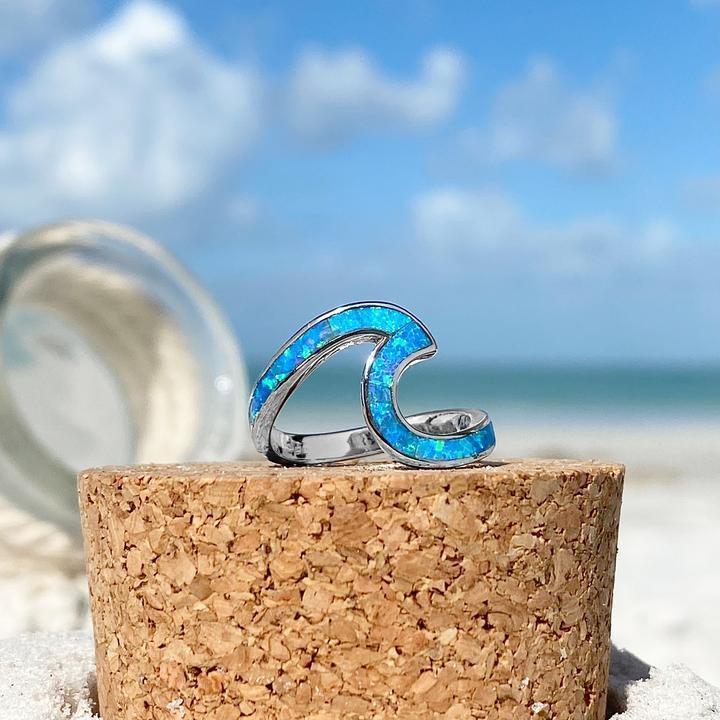 Ondina silver sea wave ring with blue opal resting on a cork surface outdoors