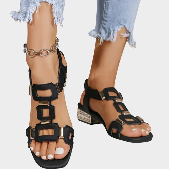 Woman wearing black block heel sandals with embellishments