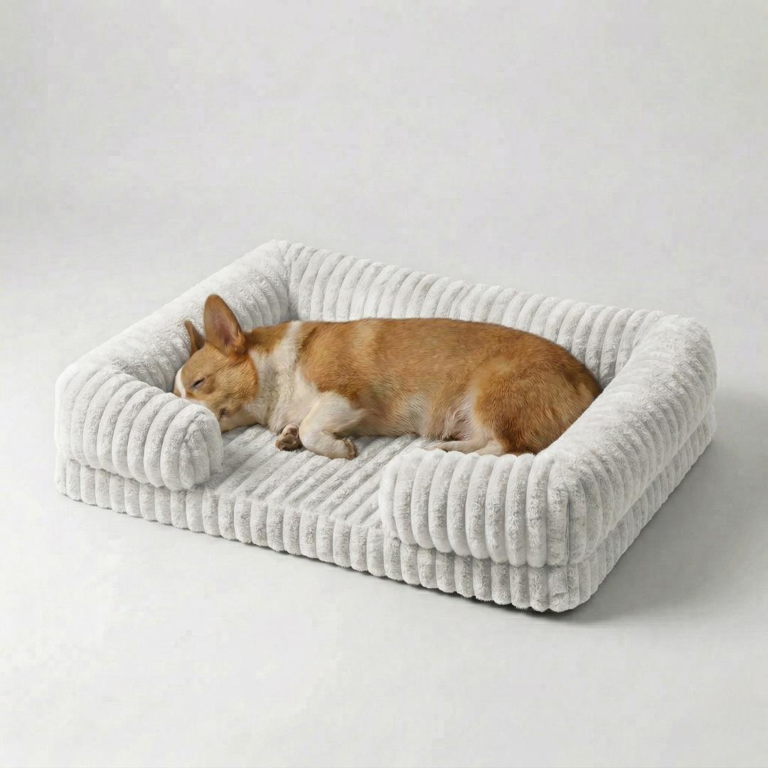 Corgi sleeping peacefully on a white ribbed sofa-style dog bed against a neutral background