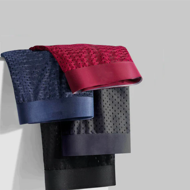 Folded men's boxer shorts in blue, red, and black hanging over a surface