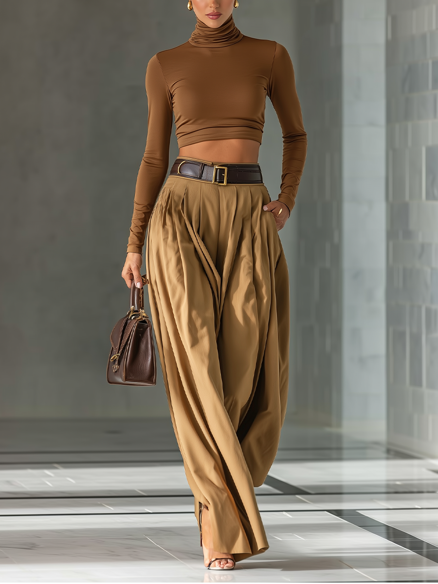 Woman wearing a brown long-sleeve crop top and wide-leg pants holding a handbag