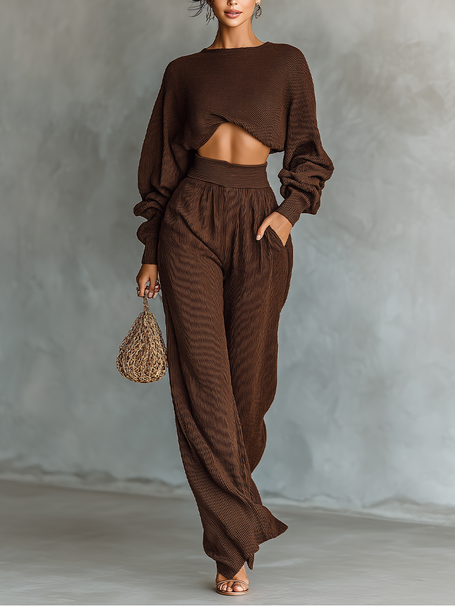 Model wearing a coffee brown knitted cropped top and wide-leg pants set holding a woven bag.