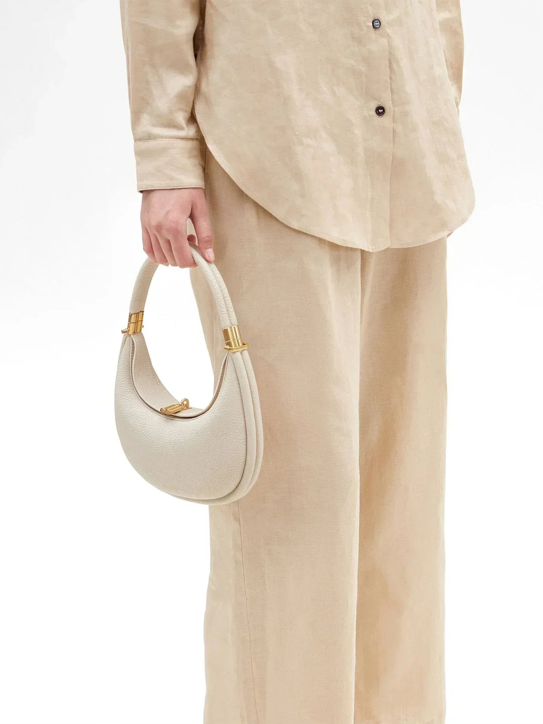 Model holding the ivory crescent handbag by its top handle