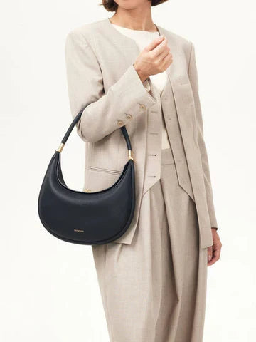 Model wearing the dark onyx crescent crossbody bag with an elegant suit