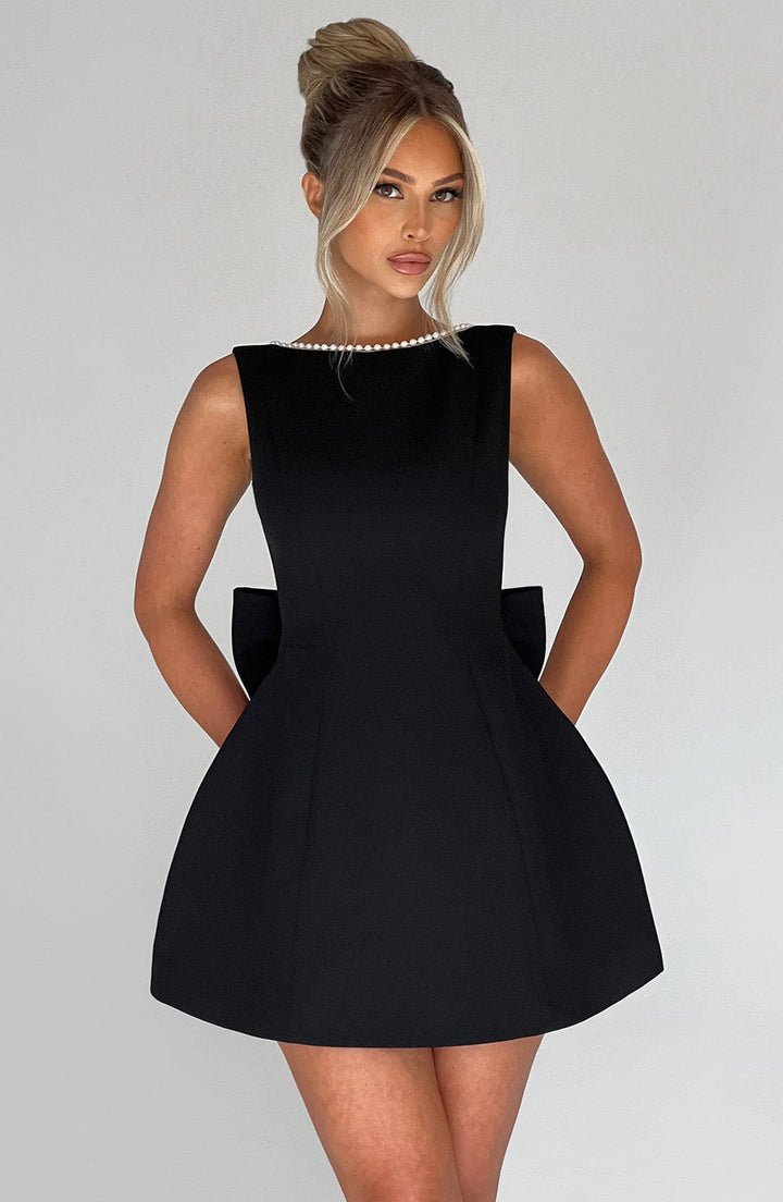 Woman wearing the black pearl trim a-line mini dress with a statement bow