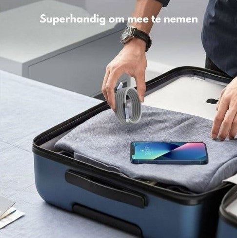 Person packing a neatly coiled charging cable into a travel bag