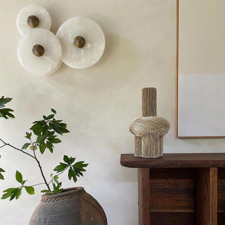 Modern round alabaster wall lamp glowing softly in a chic bedroom lighting setup