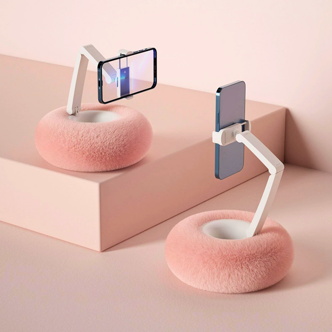 Two pink adjustable mobile phone holder pillows displaying smartphones on a surface