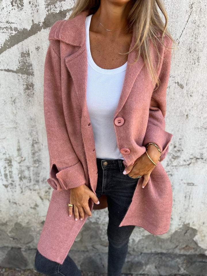Woman wearing a pink long knit coat with button closure outdoors