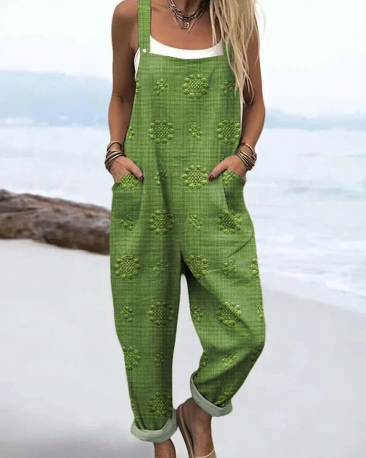 Model wearing green meadow glow floral jumpsuit by the water