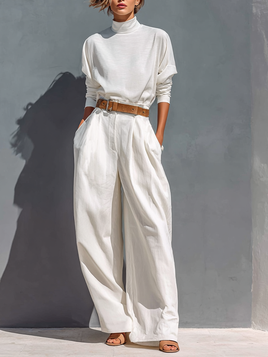 Model wearing a white high neck tee and wide leg pants set with a brown belt
