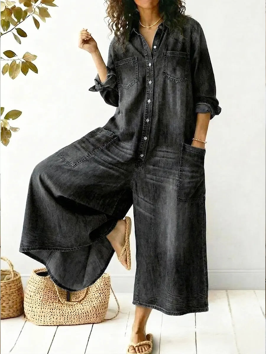 Woman wearing black wide-leg button-front jumpsuit posing with one leg raised
