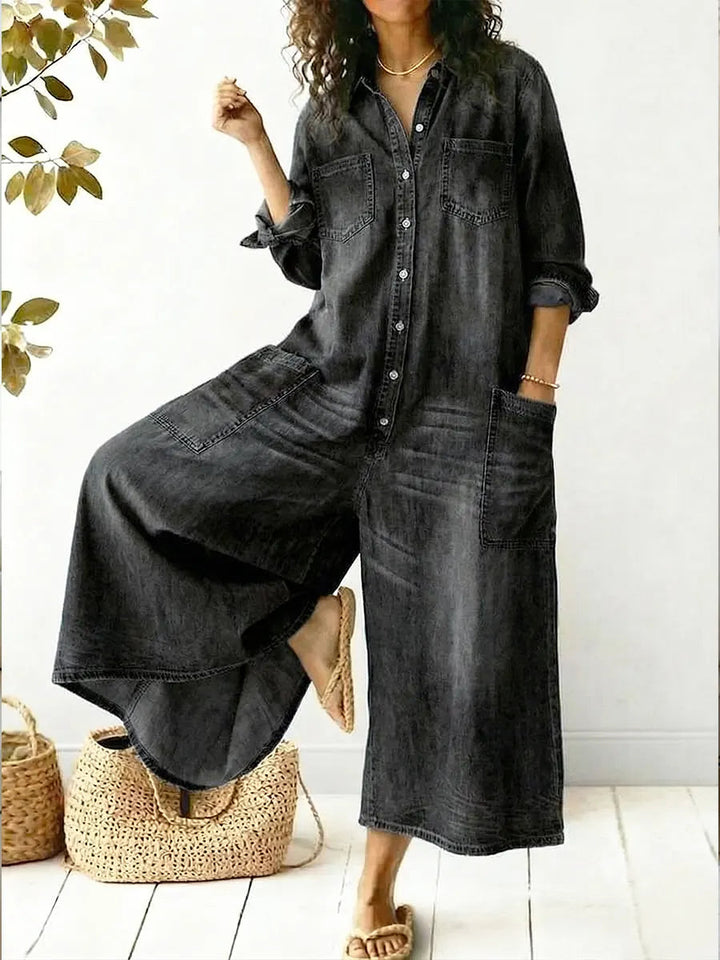 Woman wearing black wide-leg button-front jumpsuit posing with one leg raised