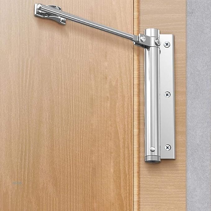 Surface-mounted silver spring door closer mounted on a wooden door frame