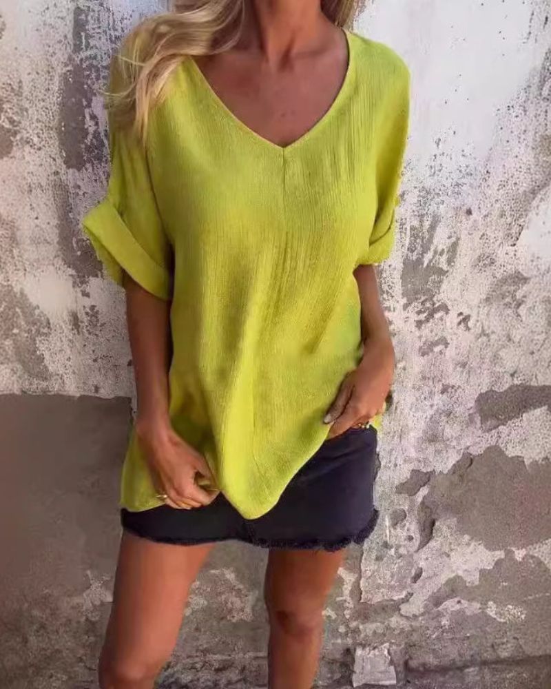 Woman wearing yellow V-neck casual flow top with dark denim skirt
