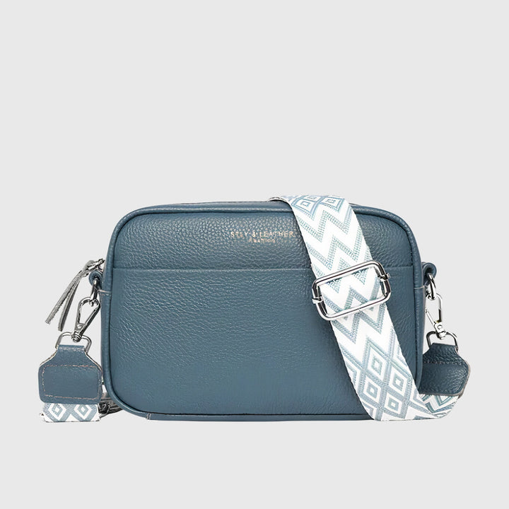 Women's crossbody handbag shown from the side, highlighting its compact camera bag shape and durable material.