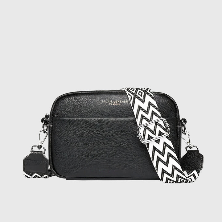 Women's black crossbody handbag featuring a patterned wide strap and silver hardware