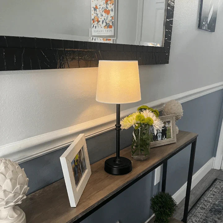Portable retro LED table lamp emitting warm ambient light in a cozy bedroom setting