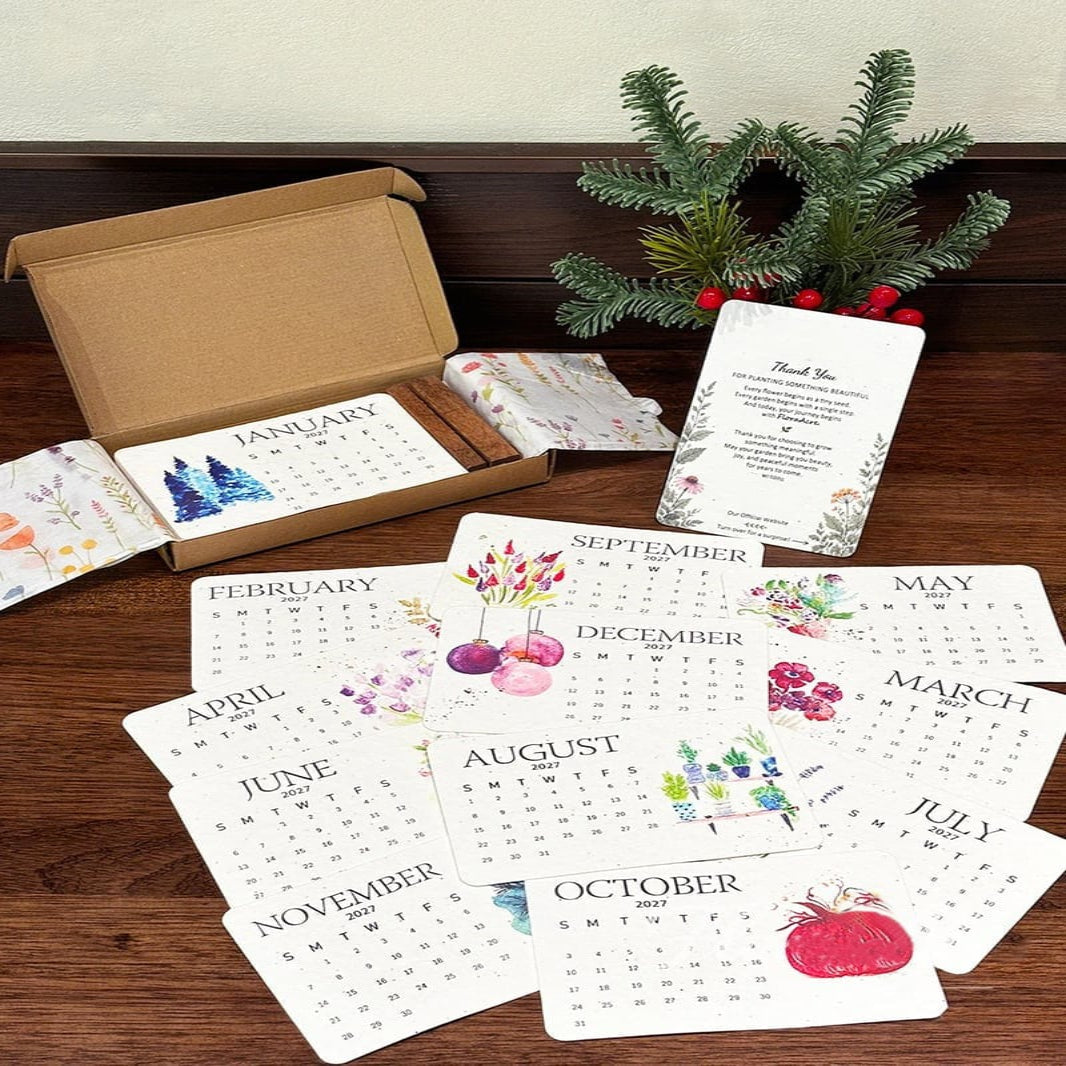 Full set of the 2027 plantable seed paper calendar cards arranged neatly around an open gift box and festive pine branches