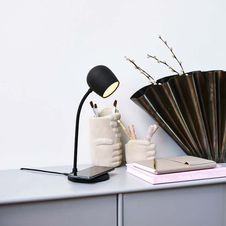 SmartGlow LED Lamp in Black with phone charging on base on a desk
