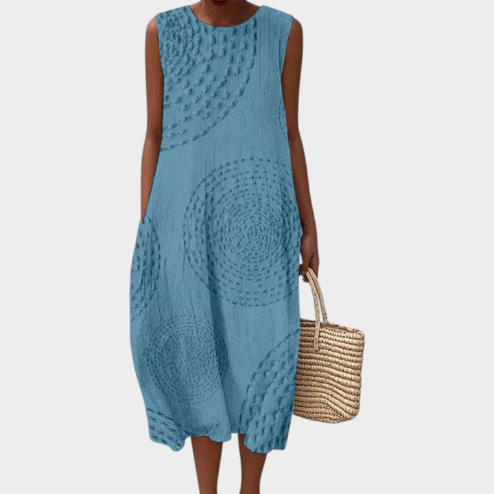 Woman wearing sky blue sleeveless textured summer midi dress with woven bag