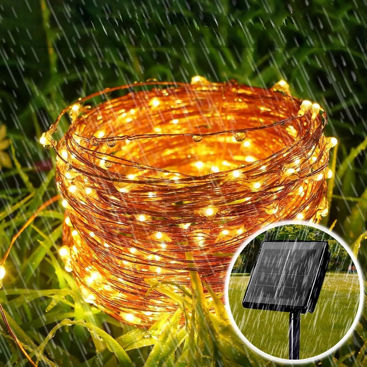 Festive solar string lights hanging along a wooden fence in a backyard