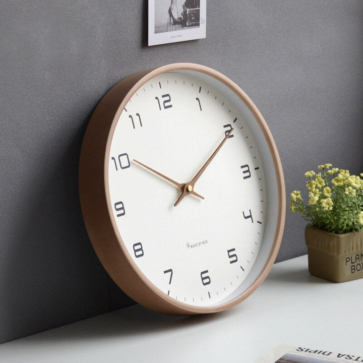 Close up view of the round wooden wall clock with clear white dial.