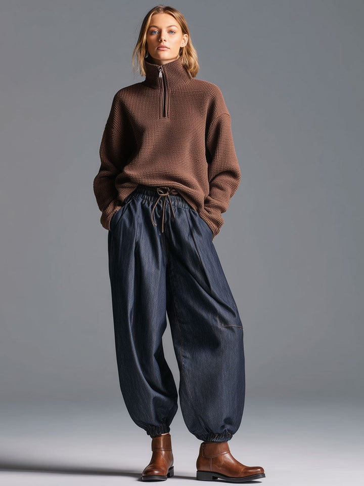Full view of woman wearing retro navy blue lantern trousers and half-zip sweater