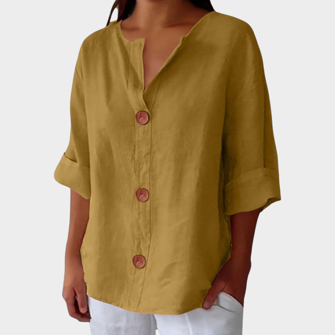 Woman wearing yellow relaxed 3/4 sleeve button up blouse with white trousers