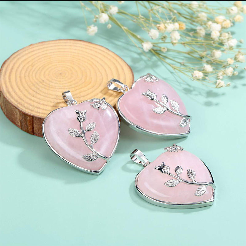 Multiple Rose Quartz heart gemstone pendants arranged on a decorative surface.