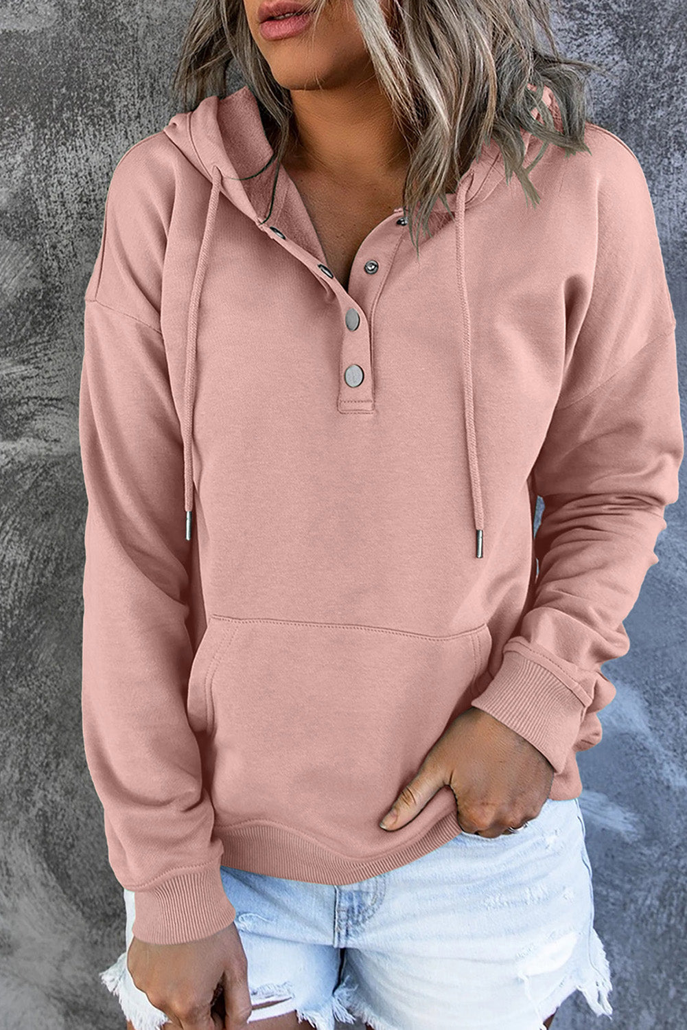 Woman wearing cozy pink hooded sweater with button collar and front pocket