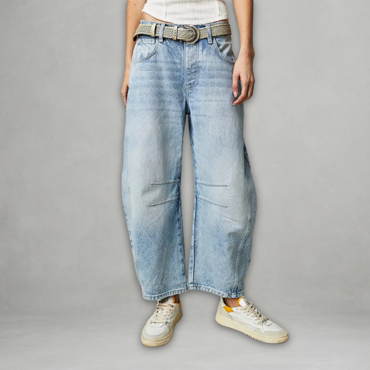 Woman showcasing light blue baggy jeans with a woven belt and sneakers