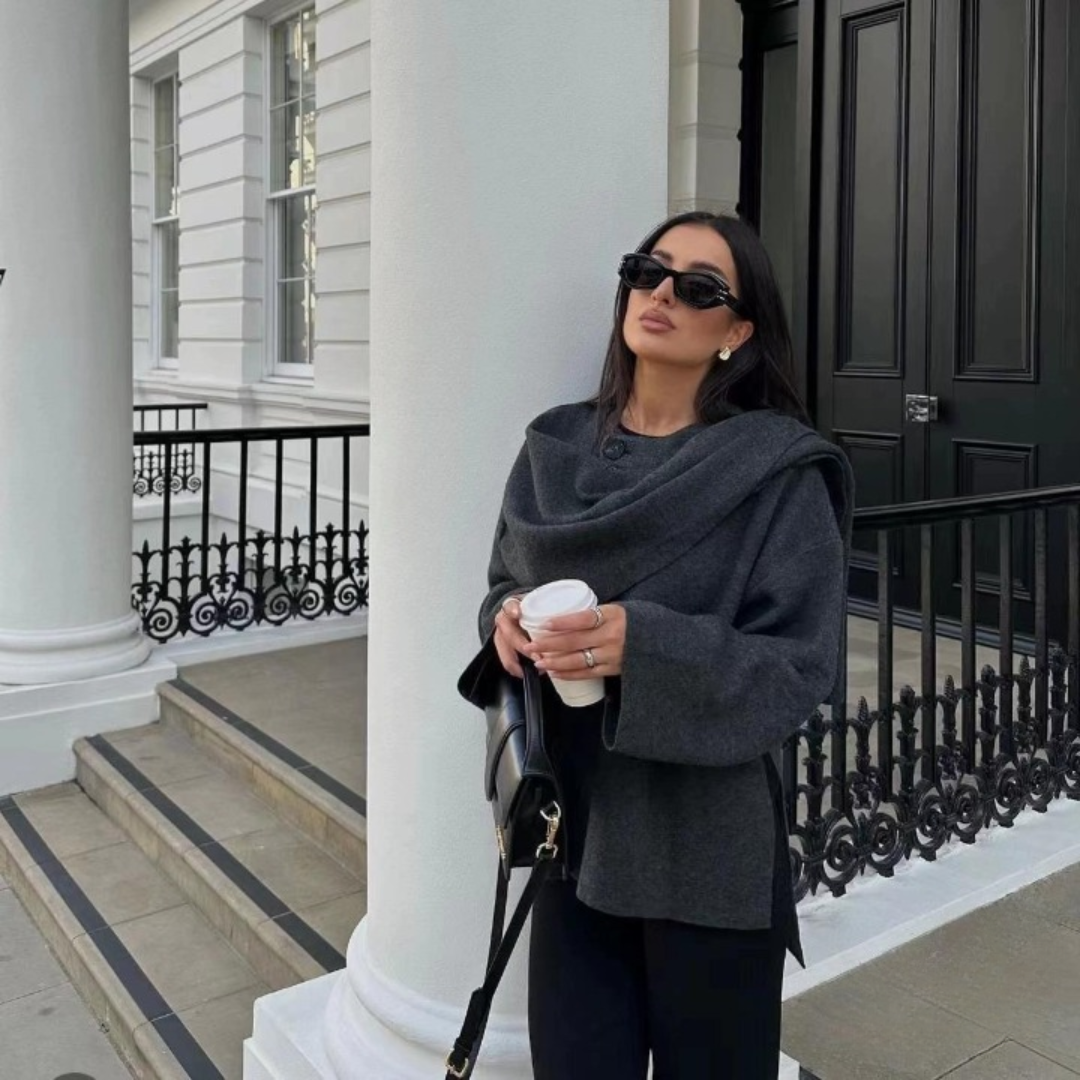 Stylish woman posing in oversized dark grey wool jacket near columns